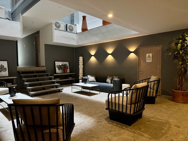 Ein modernes Wohnzimmer mit Sofa, Sesseln, Couchtisch und Treppe.