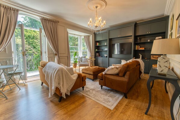 A living room with a chandelier, a sofa, a coffee table, and a TV. - Host Stay Kings Cloisters (York)
