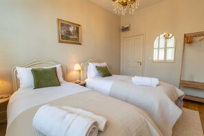 A hotel room with two beds, a chandelier, a painting, and a window with blinds. - Host Stay Kings Cloisters (York)