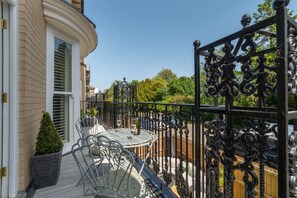 A balcony with a metal table and chairs, a potted plant, and a decorative metal fence. - Host Stay Kings Cloisters (York)
