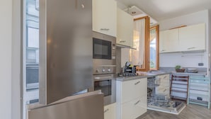 Cozinha moderna com eletrodomésticos de aço inoxidável, armários brancos e máquina de lavar louça.