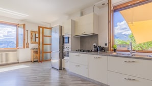 Uma cozinha moderna com armários brancos, eletrodomésticos de aço inoxidável e uma grande janela com vista para o exterior.