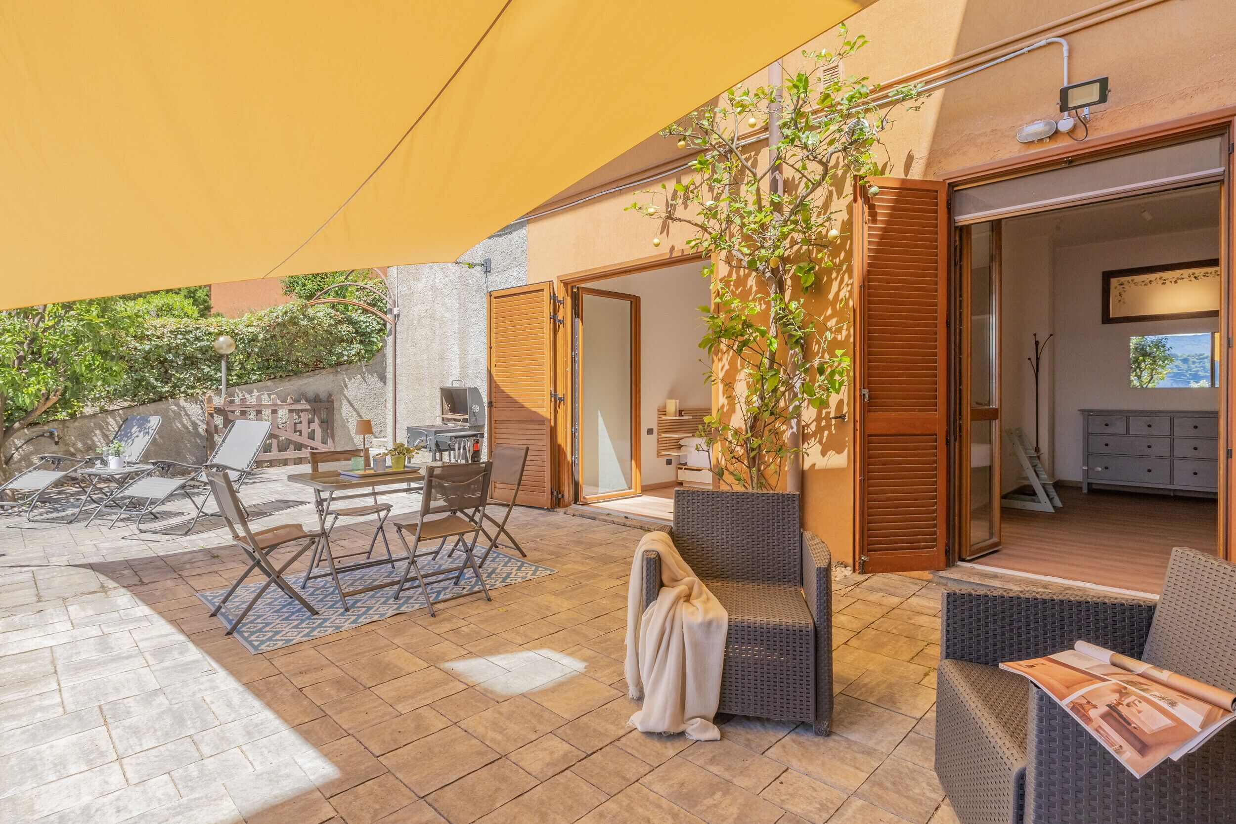 Une terrasse extérieure avec un ensemble de mobilier de jardin, des meubles en osier et un espace abrité.