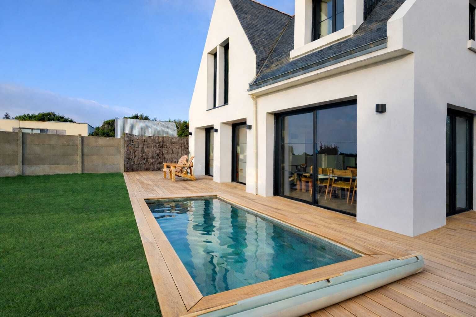 Een modern huis met een zwembad, een terras met stoelen en een stenen muur.