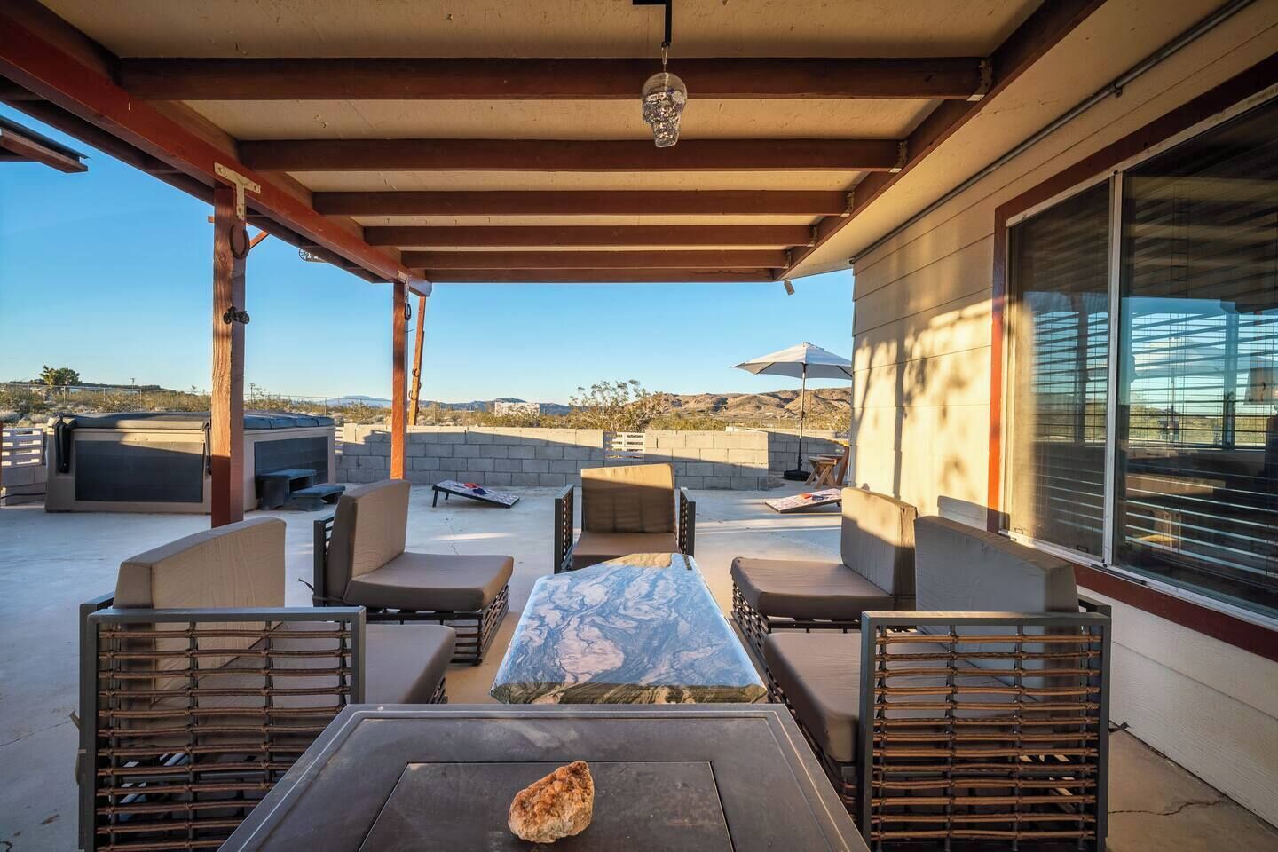 En udendørs terrasse med et bord, stole og en grill.