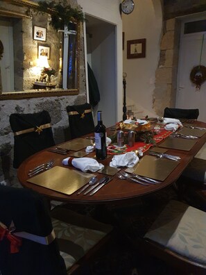 A dining table set with chairs, a bottle of wine, and a festive centerpiece.