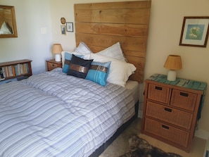 A neatly made bed with striped bedding, a wooden headboard, and a bedside table with a lamp. - Bed and Breakfast 'The Four Winds - Les Quatre Vents' with Shared Terrace, Shared Garden and Wi-Fi (Francescas)