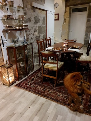 Ein Essbereich mit einem runden Tisch, Stühlen, einem Teppich, einem Hund und einer Wand mit einer Uhr.