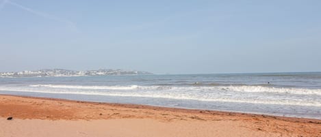 A beach with a clear sky, waves, and a distant shoreline.