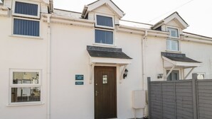 Un bâtiment avec une porte marron, des murs blancs et une entrée pavée de briques.