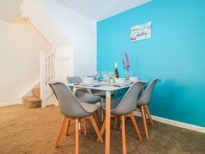 Un coin repas avec une table ronde, des chaises grises, un mur d’accent bleu et un escalier.