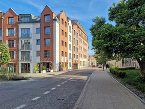 Eine Reihe moderner mehrstöckiger Gebäude mit einem gepflasterten Bürgersteig und einer von Bäumen gesäumten Straße.