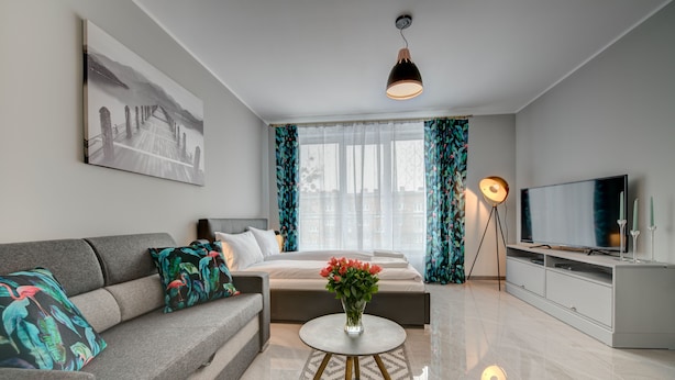 Une chambre d’hôtel moderne, équipée d’un lit, d’un canapé, d’une télévision et ornée d’un tableau au mur.