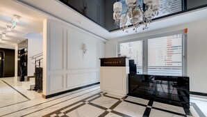 Un hall d’entrée spacieux, doté d’un sol en marbre à carreaux, d’un lustre et d’une enseigne indiquant « TARTACZNA 3 ».