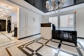 Eine großzügige Lobby mit einem Schachbrettmuster aus Marmor, einem Chandelier und einem Schild mit der Aufschrift 'TARTACZNA 3'.