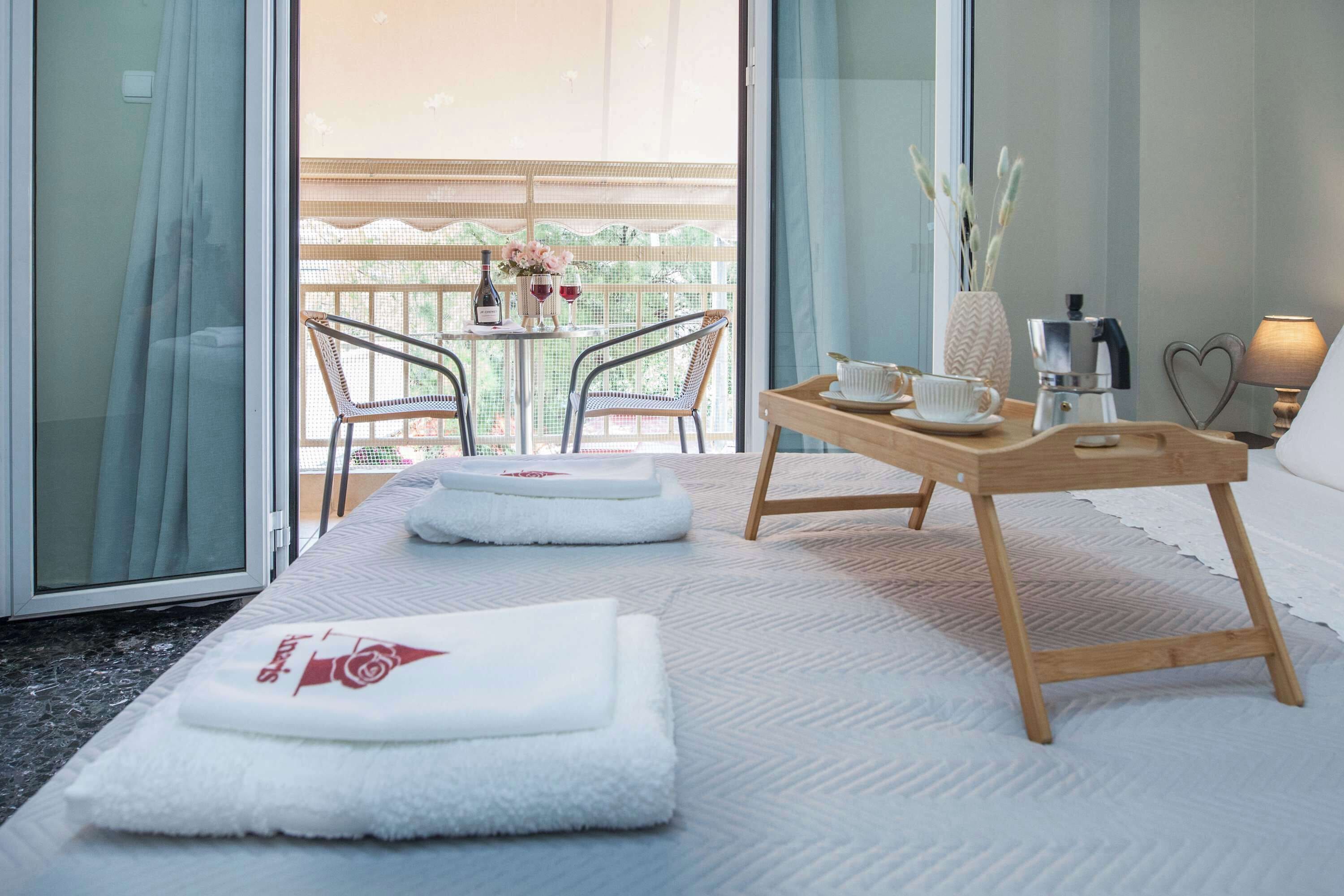Ein Hotelzimmer mit Bett, einem kleinen Tisch mit Tablett, einer Kaffeemaschine und Blick auf den Balkon.