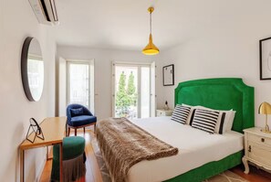 Ein Schlafzimmer mit Bett, Schreibtisch, Stuhl, Nachttisch und einer Pendelleuchte.