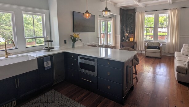 A kitchen with a large island, pendant lights, and a view of the outdoors. - Modern Downtown Living with Panoramic River Views (Wilmington)