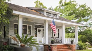 A house with a porch, a large potted plant, and an American flag. - Modern Downtown Living with Panoramic River Views (Wilmington)