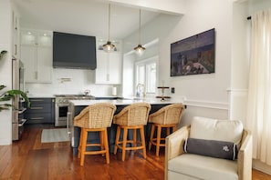 A modern kitchen with white cabinets, a central island, and bar stools.