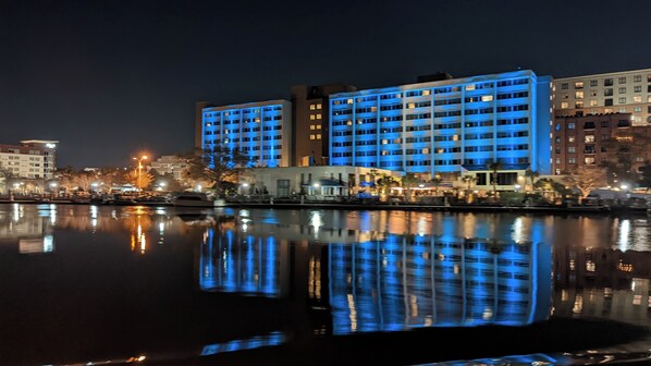 A waterfront hotel with multiple floors, a reflection in the water, and a night-time setting. - Modern Downtown Living with Panoramic River Views (Wilmington)