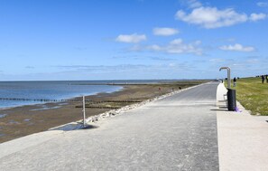 Ein Küstenweg mit freiem Blick auf das Meer, einer Grünfläche und einem befestigten Weg.
