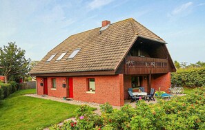 Ein rotes Backsteinhaus mit geneigtem Dach und einer Veranda.