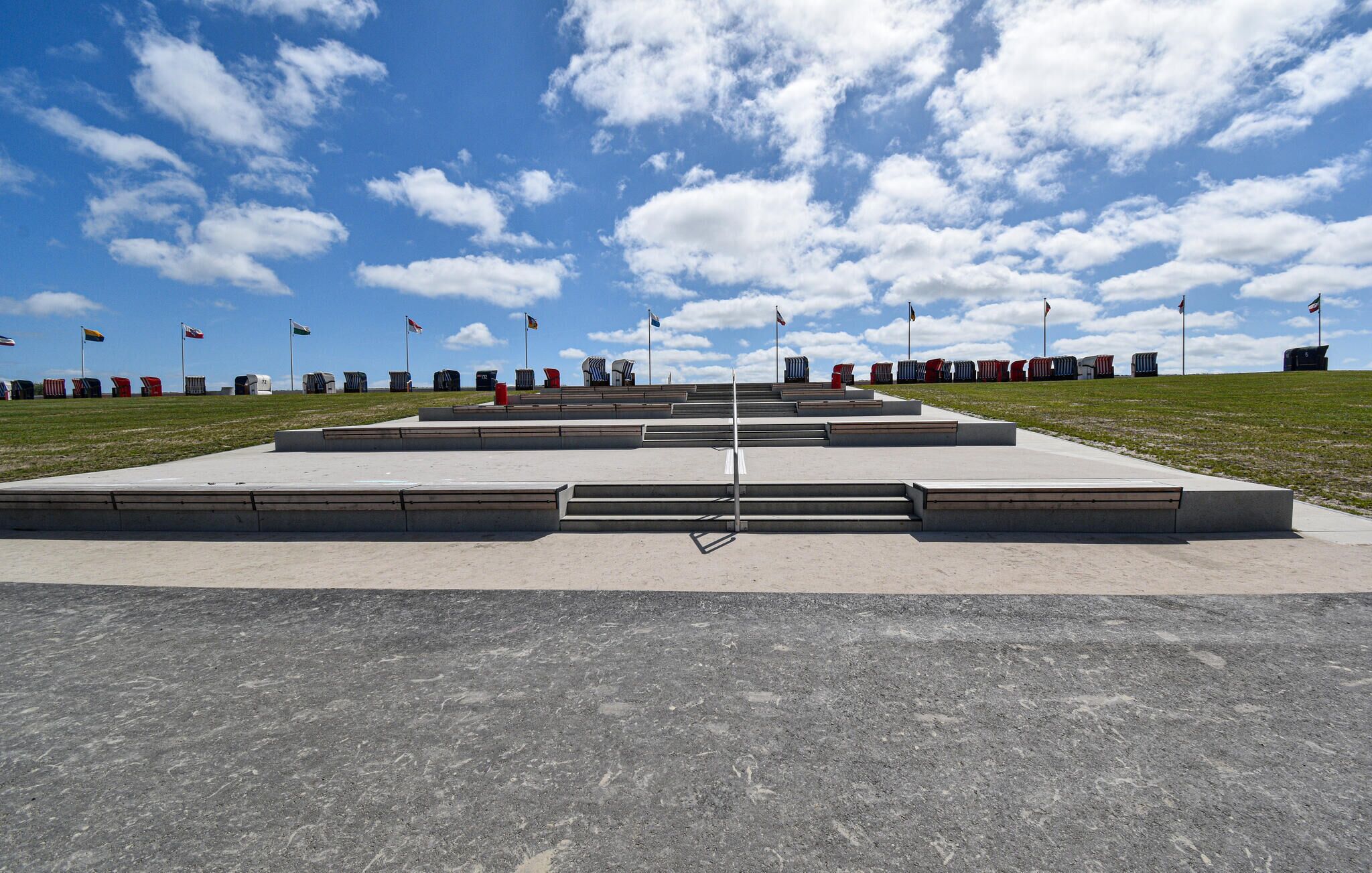 Un memoriale con una scalinata che conduce a un monumento centrale, circondato da bandiere e un cielo sereno.