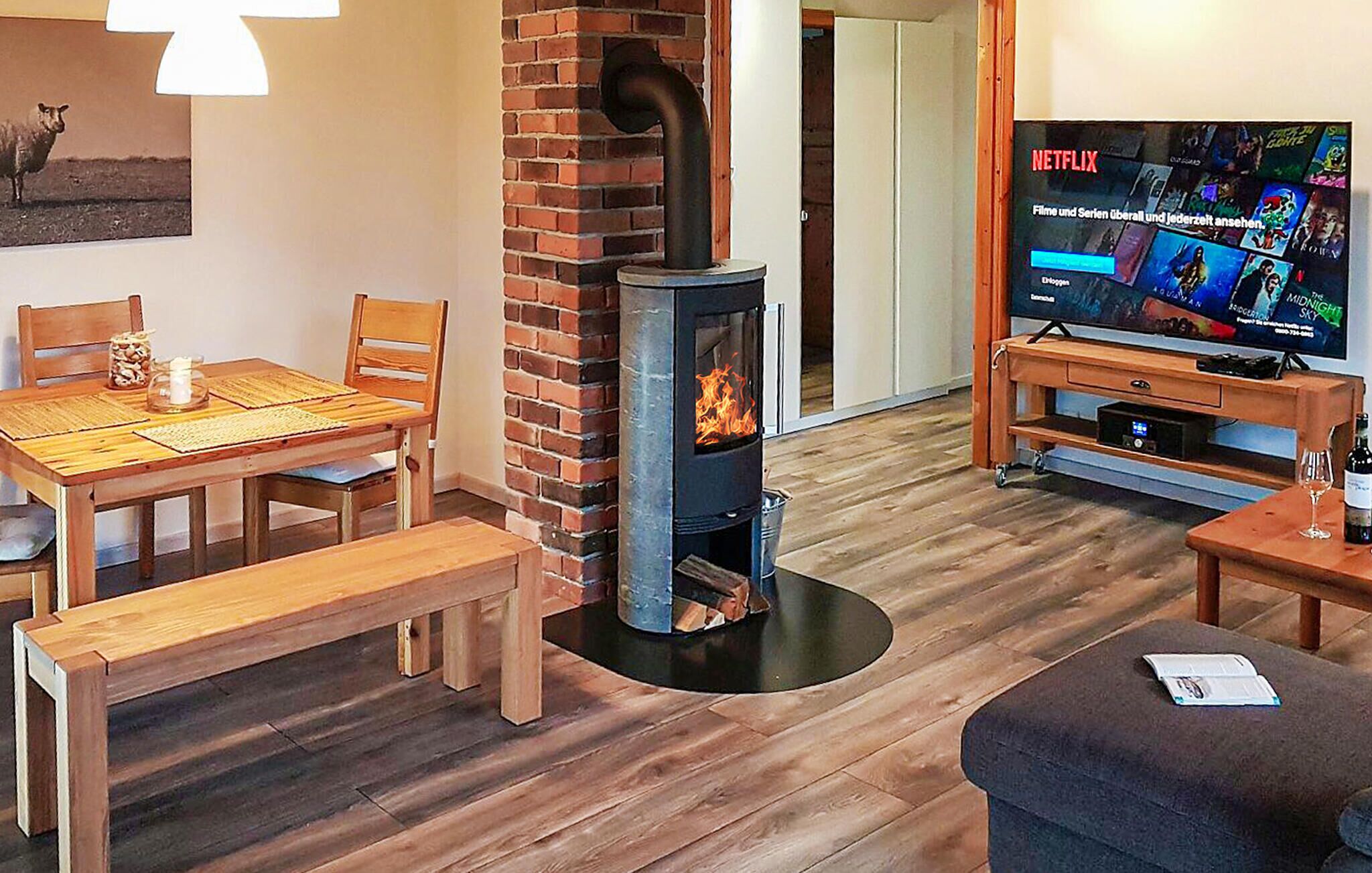 Ein gemütliches Wohnzimmer mit Kamin aus Backstein, einem Holzesstisch und einem Fernseher.