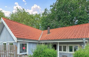 Ein Haus mit rotem Ziegeldach, Schornstein und einer Veranda mit hängenden Pflanzen.