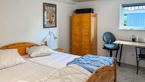 Ein Schlafzimmer mit Bett, Kleiderschrank, Schreibtisch und Stuhl sowie einem Fenster.