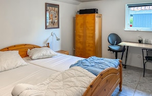 Ein Schlafzimmer mit Bett, Kleiderschrank, Schreibtisch und Stuhl sowie einem Fenster.