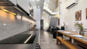 Eine moderne Küche mit Edelstahlgeräten, ein Essbereich mit einem Holztisch, gedeckt für zwei Personen, und eine Treppe, die zu einer oberen Ebene führt.