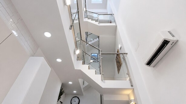 Ein mehrgeschossiges Interieur mit einer Treppe, einer Uhr und einer Klimaanlage.