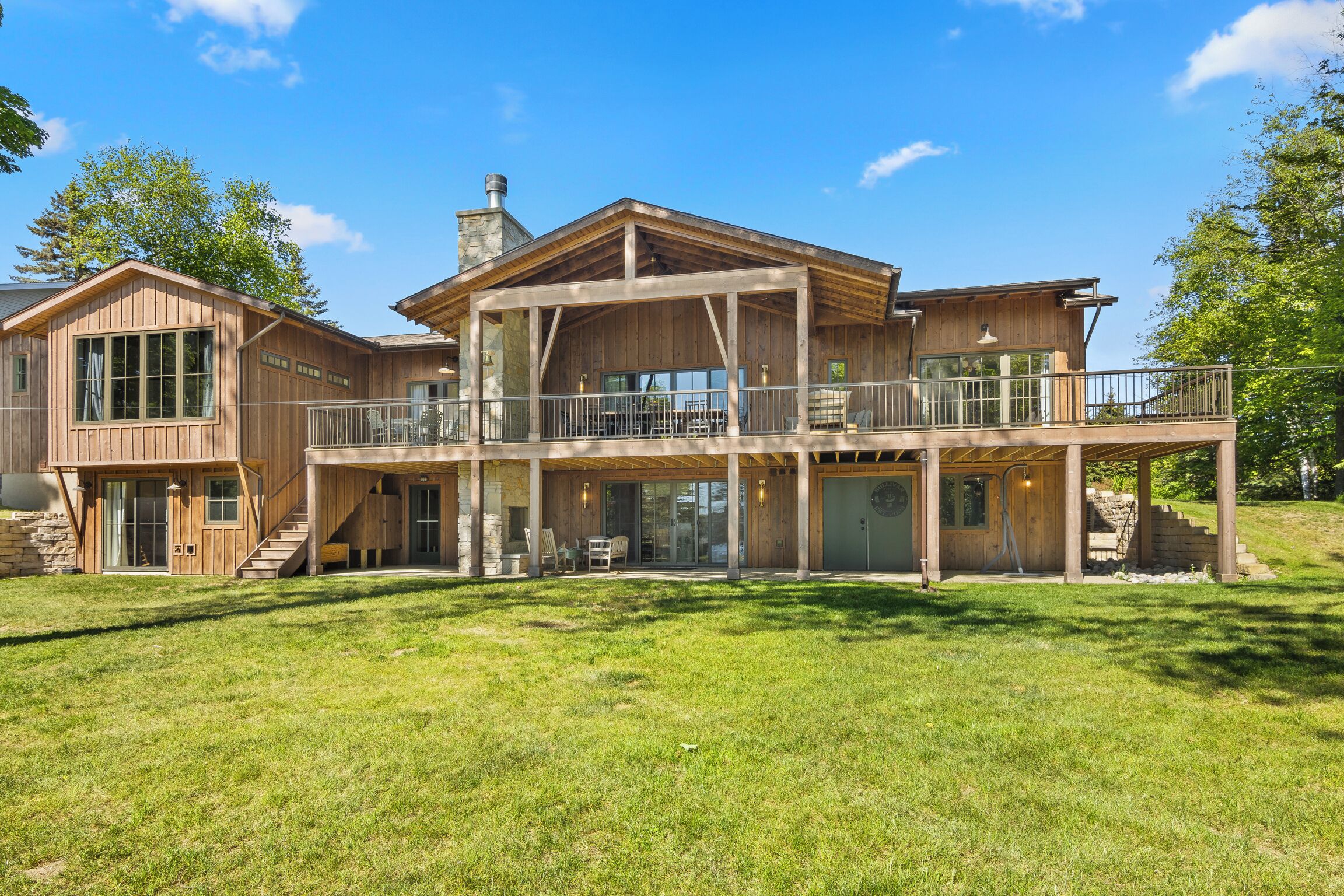 A large wooden house with multiple levels, a covered porch, and a spacious outdoor area.