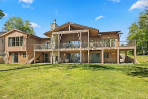 Een groot houten huis met meerdere verdiepingen, een overdekte veranda en een ruim buitengebied.