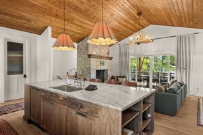 Een moderne keuken met een centraal eiland, houten kastjes en hangende lampen.