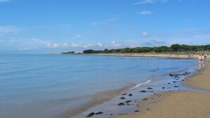 A beach with clear water, a sandy shore, and a distant shoreline with buildings and greenery. - Ca rustica in Chioggia (Chioggia)