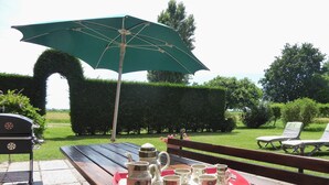 An outdoor patio with a wooden table, a green umbrella, and a grill. - Ca rustica in Chioggia (Chioggia)