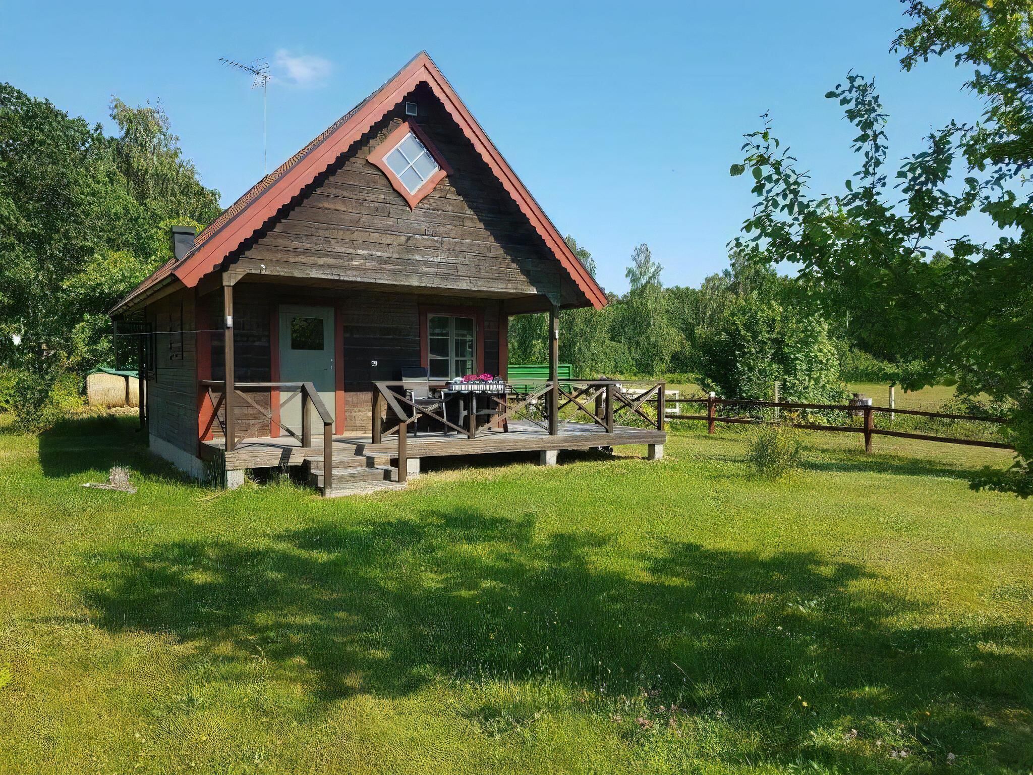 A wooden cabin with a porch, a small table, and a chair.