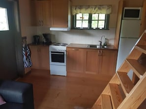 A kitchen with wooden cabinets, a stove, a sink, and a window with a view. - Cozy holiday home on beautiful Öland. (Löttorp)
