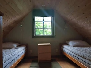 A small attic bedroom with two single beds, a window with a view of greenery, and a wooden dresser. - Cozy holiday home on beautiful Öland. (Löttorp)
