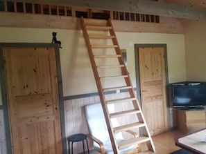 A wooden ladder in a room with wooden walls, a television, and a small stool. - Cozy holiday home on beautiful Öland. (Löttorp)