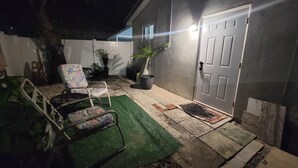 A patio area with a door, a chair, and potted plants.