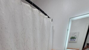A bathroom with a toilet, a sink, a mirror, and a shower curtain.
