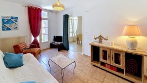 Ein Wohnzimmer mit einer Couch, einem Fernseher, einem Tisch, einer Lampe und einem dekorativen Kerzenleuchter.