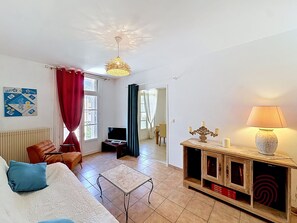 Ein Wohnzimmer mit einer Couch, einem Fernseher, einem Tisch, einer Lampe und einem dekorativen Kerzenleuchter.