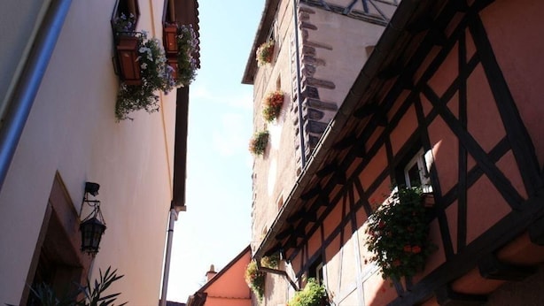 Eine schmale Straße mit traditionellen Fachwerkhäusern, eines davon mit Blumenkästen an den Fensterbänken.