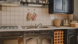 Eine Küche mit Gasherd, Spüle, dunklen Schränken und einem Weinkühlschrank.