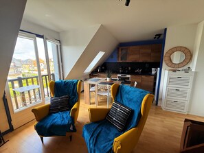 Eine moderne Loftswohnung mit Küche, Essbereich und zwei gelben Sesseln mit blauen Kissen.